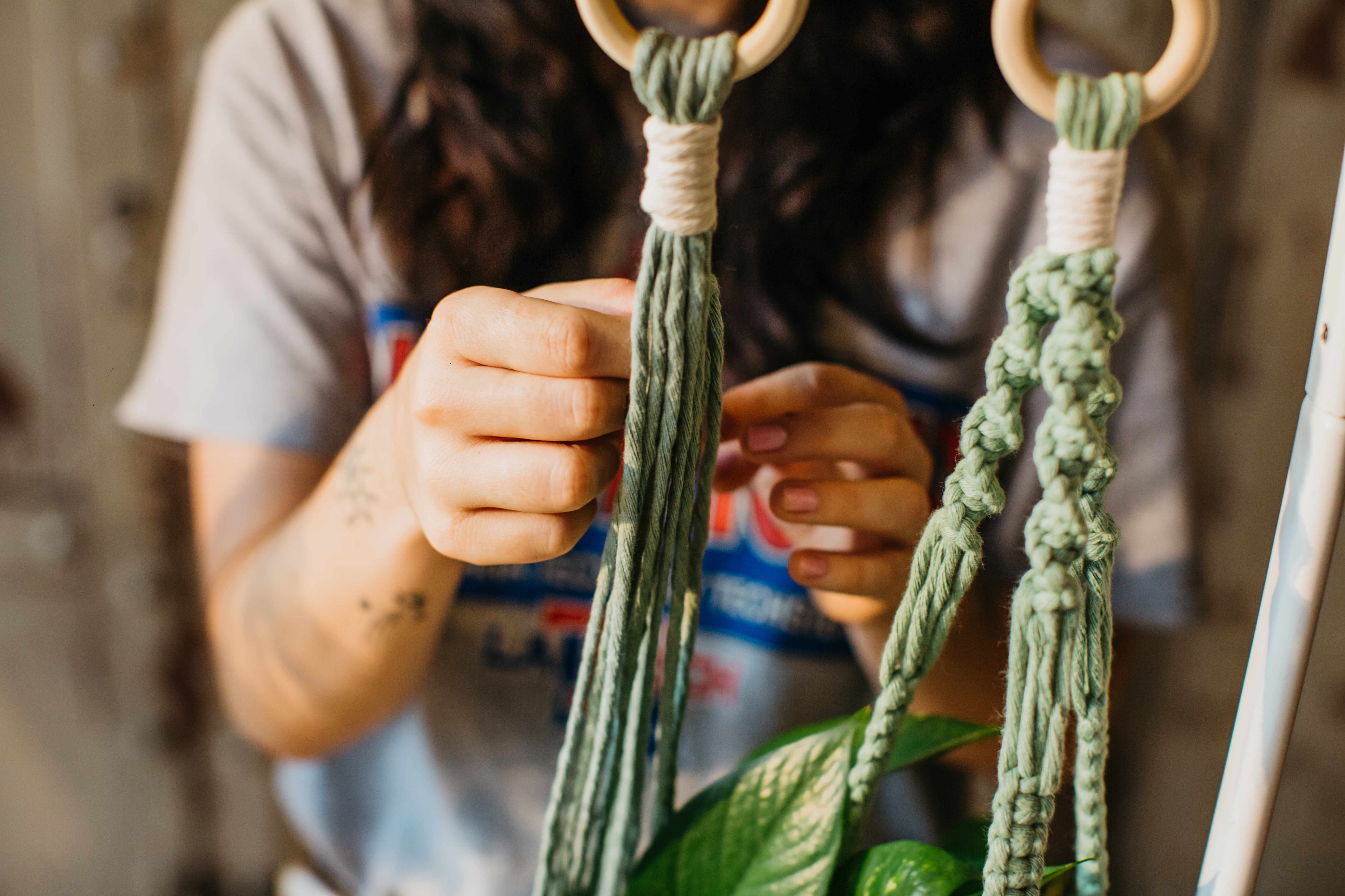 Close up of macrame plant hanger with a person behind them
